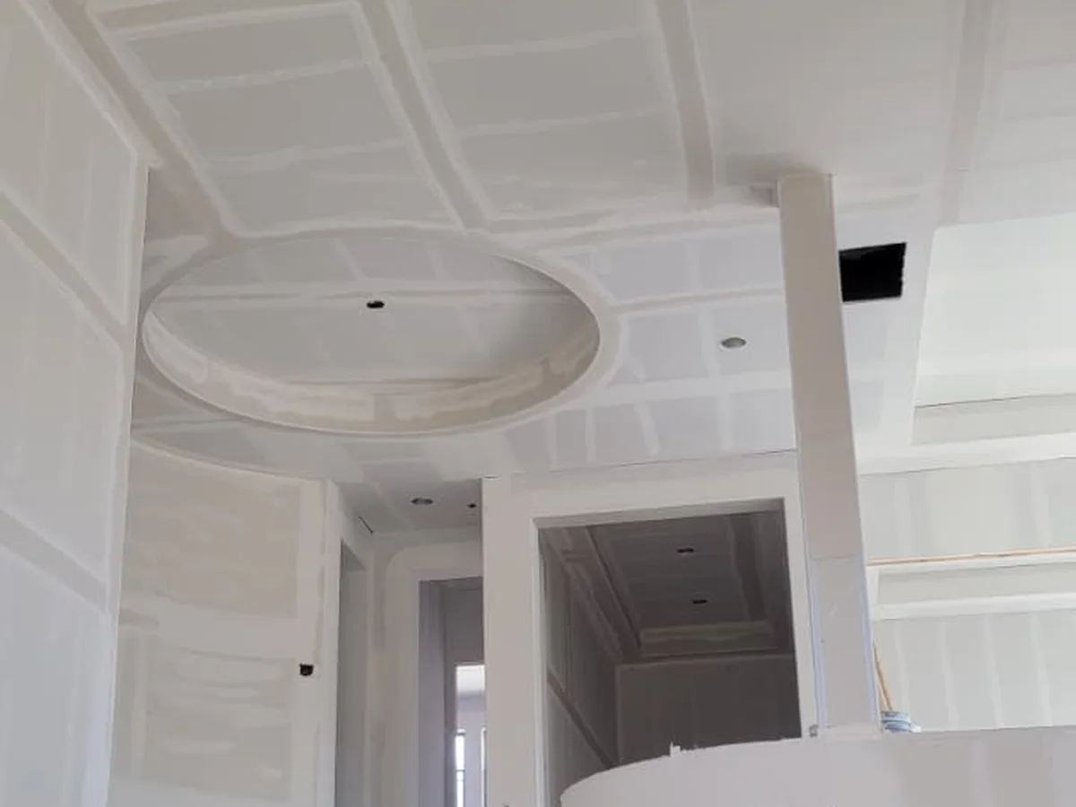 Grand foyer with a curved staircase, walls and ceiling hung and taped